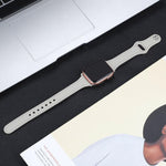 Leather replacement strap for Apple Watch placed on a desk next to a laptop and magazine.