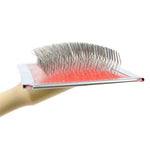 Manual pet grooming brush with curved needled bristles and ergonomic wood handle for comfortable pet grooming.